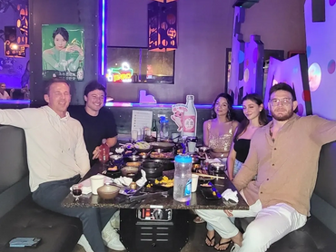A group of people smiling at their table full of food and drinks.