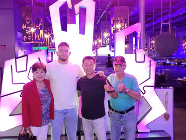 A group of four smiling with their arms on each other's shoulders.