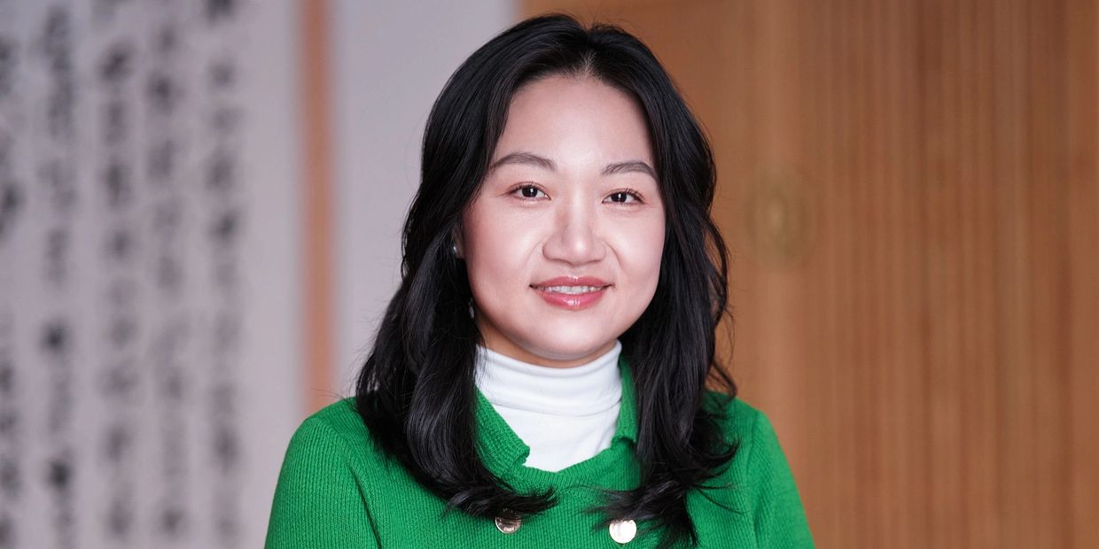 Smiling woman in green sweater with black hair.
