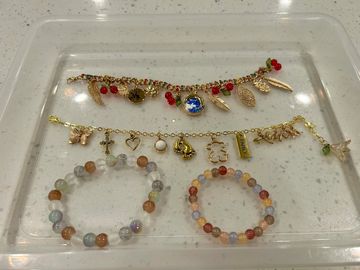 Four assorted bracelets with charms and beads on a clear tray.
