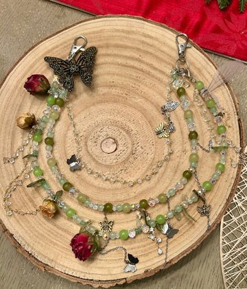 Handcrafted beaded necklaces with butterfly charms and dried roses on wooden slice.