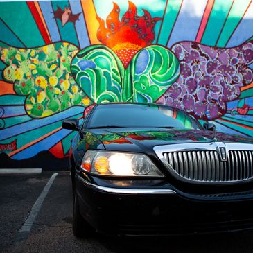 Lincoln Town Car parked in front of Sacred Heart mural in Tucson, Arizona.