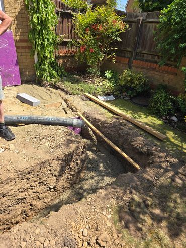 Concrete being poured into a garden trench for construction.