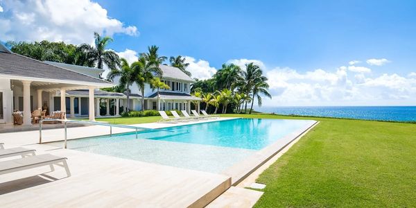 Casa moderna con vista al mar, amplia piscina y rodeada de palmeras.