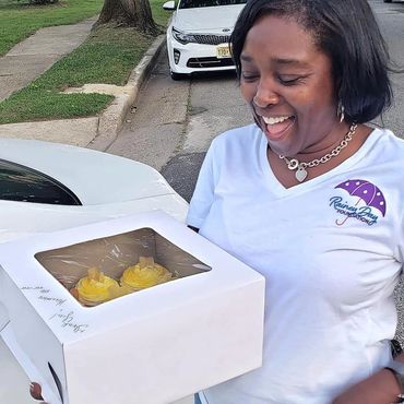 a woman holding a box of cupcakes