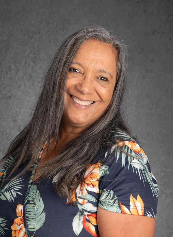 Smiling woman with long gray hair wearing a floral shirt.