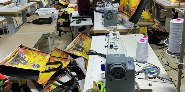 Workers sewing colorful bags in a busy workshop with sewing machines.
