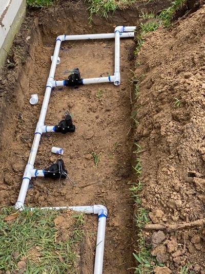 PVC irrigation system with valves installed in a dug trench.