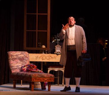 Man performing dramatic monologue on stage with vintage setting.