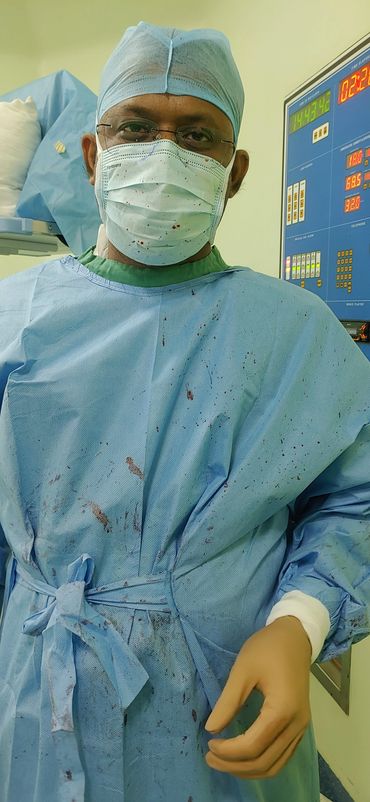 Surgeon in scrubs with bloodstains in operating room.