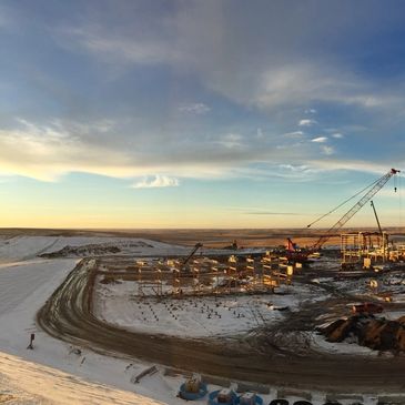 Construction site in a snowy, barren landscape during sunset.