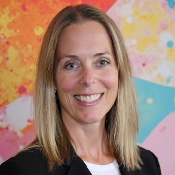 Professional woman smiling against a colorful abstract background.