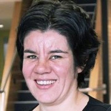 Smiling person with short dark hair in a casual setting.