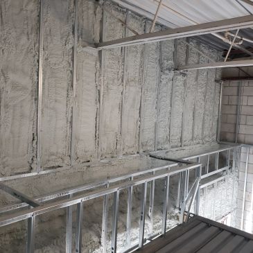Empty metal scaffolding stands against a concrete wall in an unfinished building.