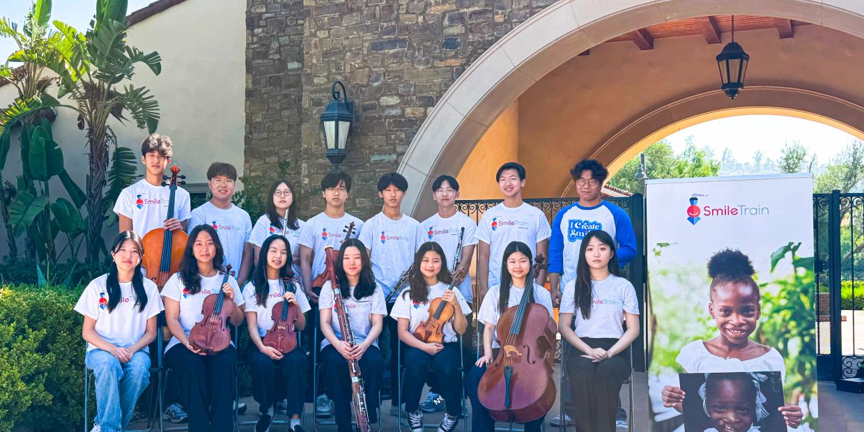 Group photo of young musicians with instruments and Smile Train shirts.
