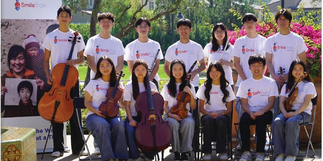 Group photo of young musicians wearing Smile Train shirts with various string and wind instruments.