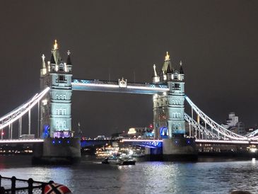 The Tower Bridge in London illuminated at night over the Thames River.