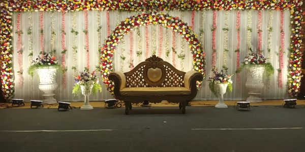 Decorative wedding stage with floral arrangements and vintage sofa.