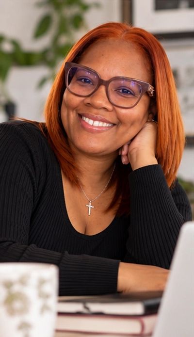 Smiling woman with glasses and red hair.