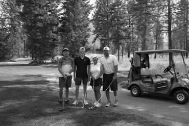 Four golfers posing next to a golf cart at the Talking Rock Golf Course at a golf tournament  