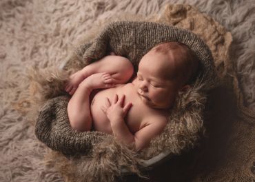 Newborn baby peacefully sleeping in a cozy knitted blanket.