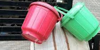 Two plastic buckets, one red and one green, leaning against a wall.