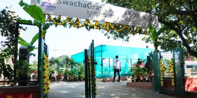 Entrance gate decorated with flowers leading to a green nursery area.