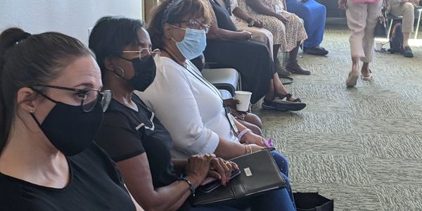People sitting closely in a waiting room, wearing masks.