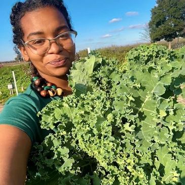 Woman holding fresh kale outside on a sunny day.