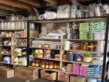 Shelves stocked with disposable kitchen supplies and condiments in storage.