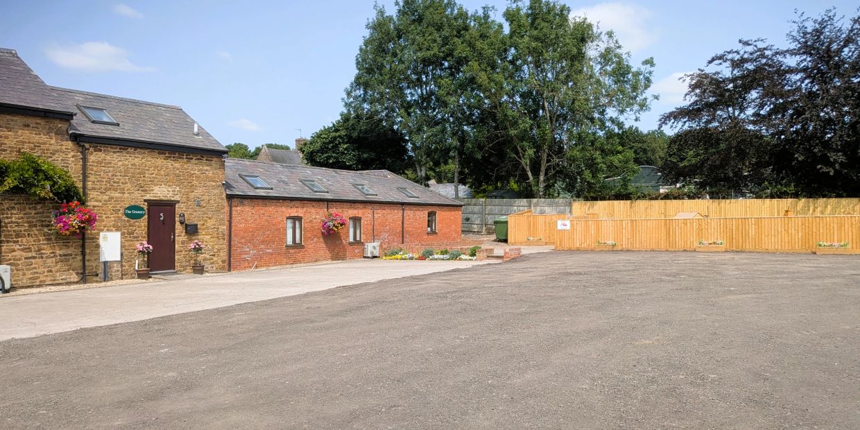 Sunny courtyard with charming brick buildings and wooden fence.