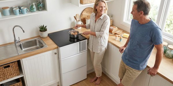 Couple cooking together in a bright, modern kitchen with wooden countertops.