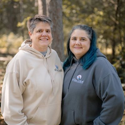 Two women smiling outdoors wearing hoodies.