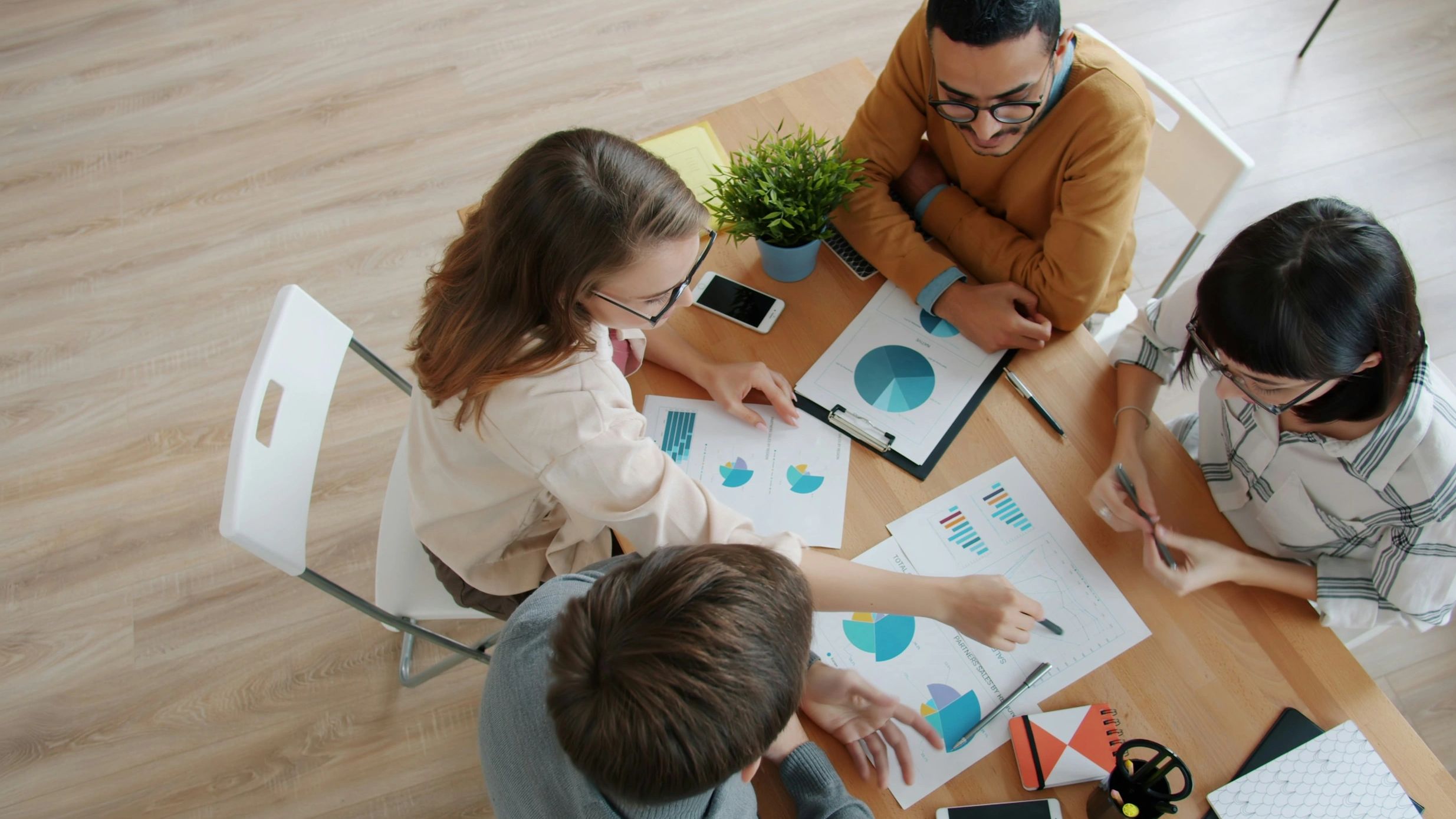 Group discussing charts and graphs at a meeting table.