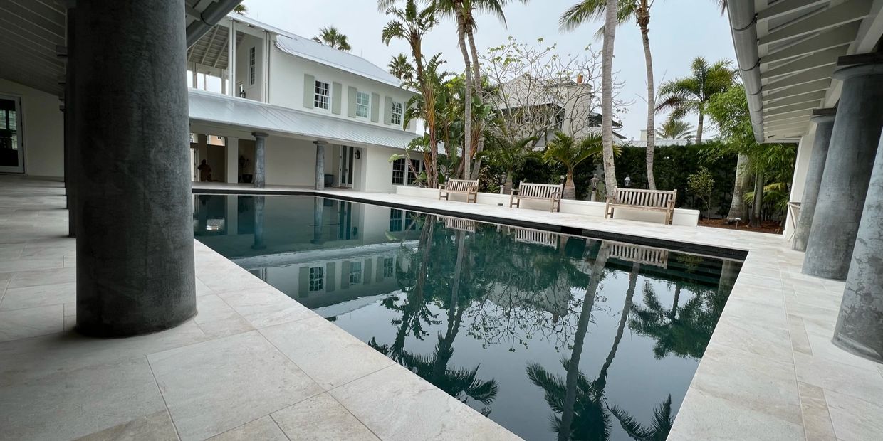 Elegant poolside area with palm trees and benches reflecting in the water.