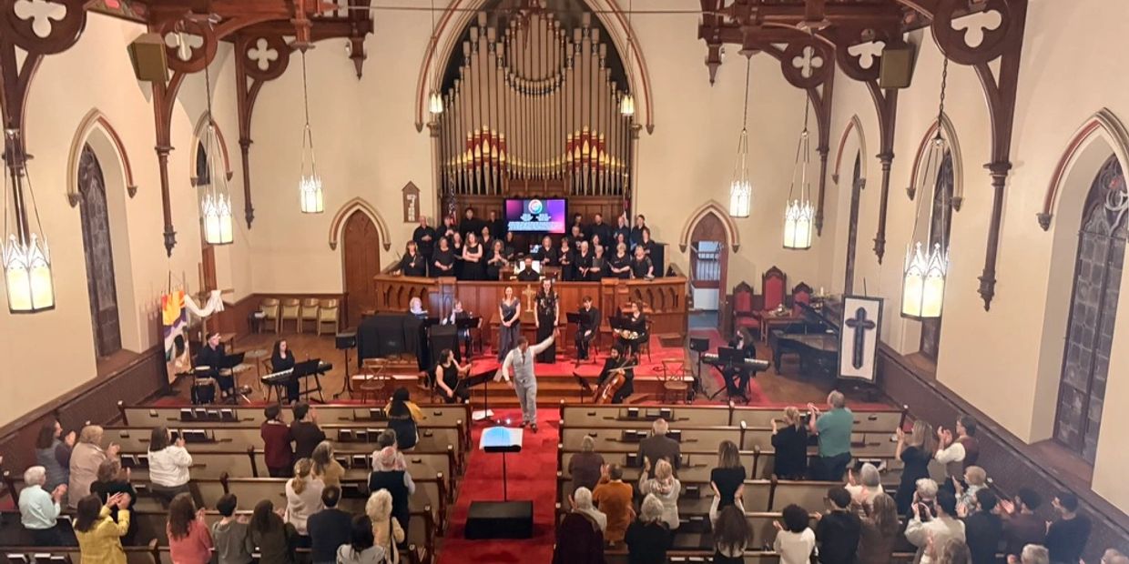 A choir and musicians perform in a church with an applauding audience.