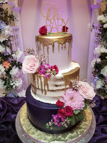 Elegant three-tier cake with pink flowers and gold drip.