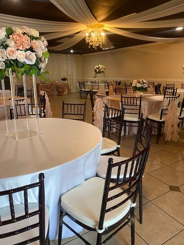 Elegant event setup with floral centerpieces and draped ceiling.