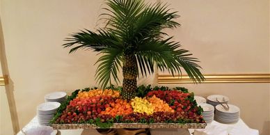 Palm tree fruit centerpiece with plates on sides.