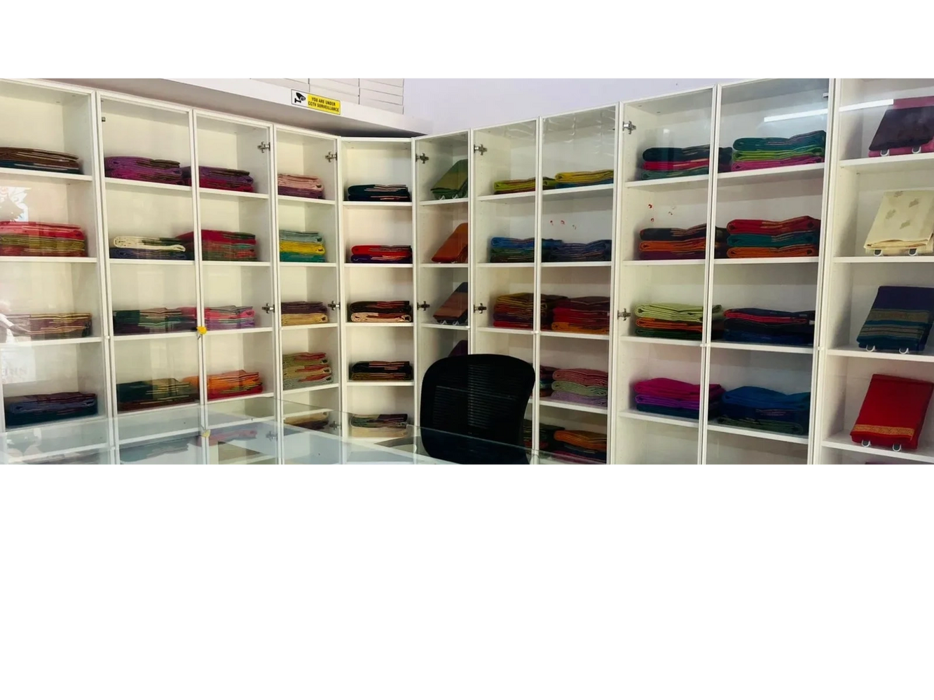 Glass cabinets filled with neatly folded colorful fabrics in a showroom.