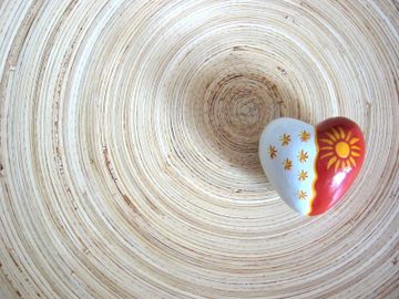 Stone heart painted red and white offset on a circular brown and white platter.
