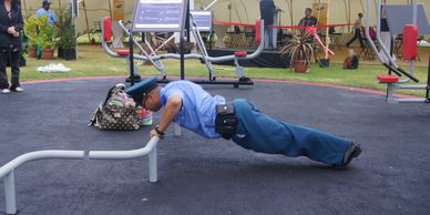 a police officer using a outdoor gym equipment to do pushups in a correctional facility/prison