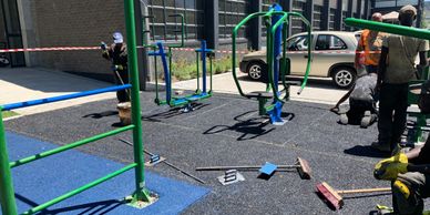 A outdoor gym equipment setup in a commercial property being installed by labourers