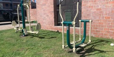 two pieces of outdoor gym equipment located on a field in an apartment complex in Ottery