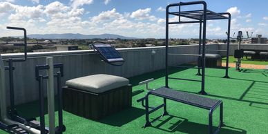 an outdoor gym located on a roof of an apartment block in a sunlit summers day