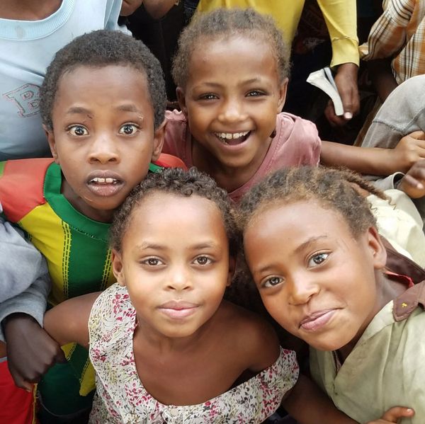 Ethiopian children huddle excitedly around a missionary.