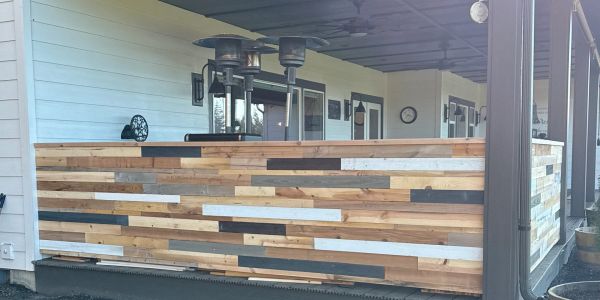 Patio with multicolored wooden railing and heaters.