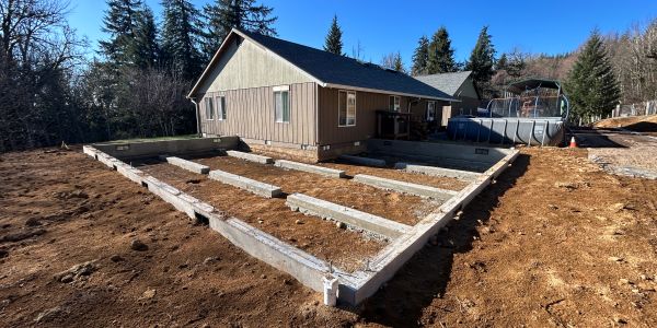 Foundation beams around a house under clear blue sky.