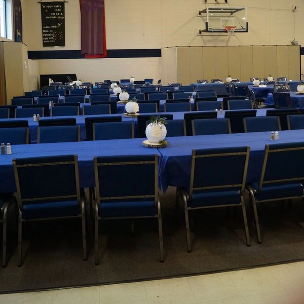 A gymnasium set up with tables and chairs for an event.
