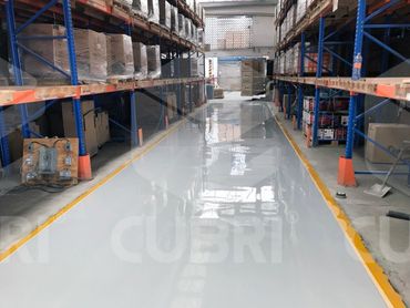 A clean, shiny warehouse aisle with blue shelving and organized boxes.